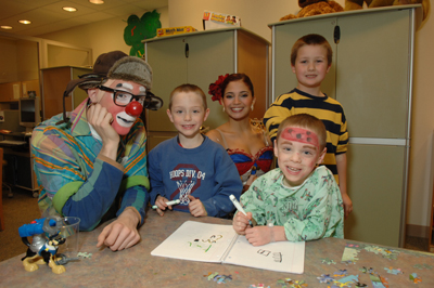 Children show visiting circus members their artwork.
