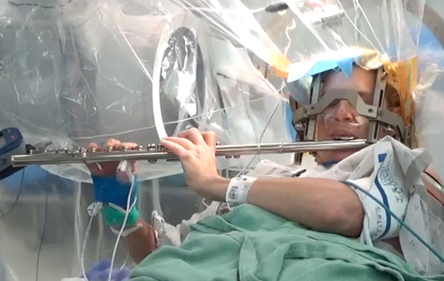 patient plays flute while undergoing surgery
