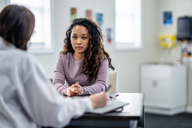 Depressed woman speaking to a doctor during a consultation in a modern medical office