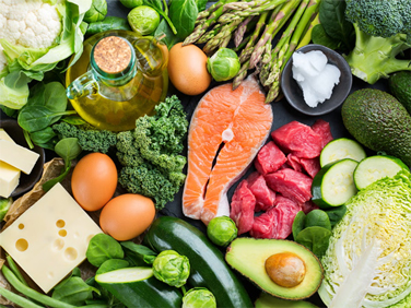 An assortment of healthy foods, including fresh vegetables, eggs, and salmon