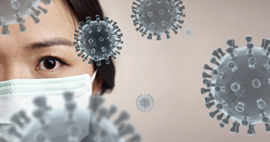 A doctor wearing a mask zoomed into her eyes with COVID-19 cells surrounding them