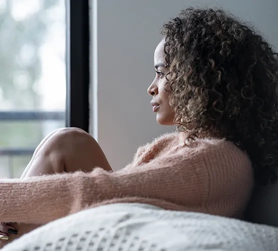 Close-up of a woman looking out a window, reflecting a sense of loneliness