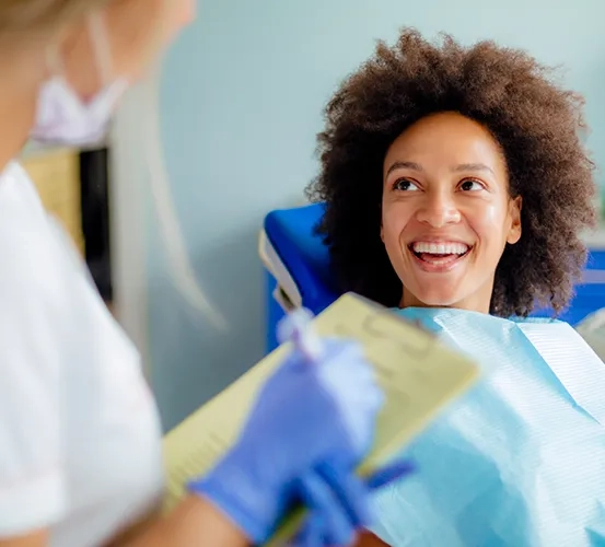 A female patient smiling comfortably while sitting in a dental chair