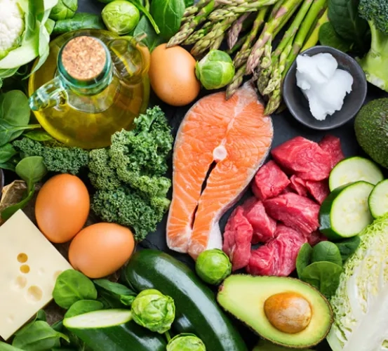 An assortment of healthy foods, including fresh vegetables, eggs, and salmon