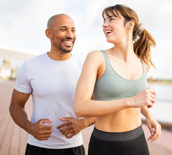 Two people smiling while jogging together outdoors