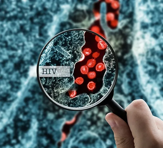 A hand holding a magnifying glass focusing on a close-up view of spherical HIV cells