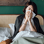 photo of woman in bed blowing her nose