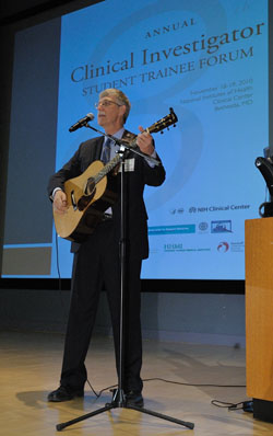 Dr. Collins playing the guitar on stage at the CIST Forum
