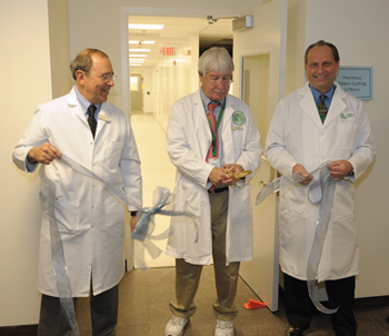 Dr. Gallin and Bob DeChristoforo hold the ribbon while George Grimes cuts into the new PDS