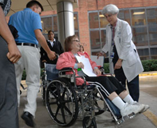 Nurse escorts woman in wheelchair while escort assists