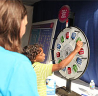 Britt Ehrhardt watches a boy spin the prize wheel in a tent at the Science Festival