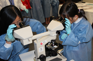 Cela (left) and KeLan Migan looking through a microscope