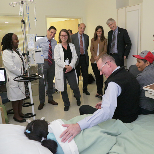 Dr. Paul Farmer (center on bed), guest speaker at the 2016 Barmes Global Health Lecture, visits pediatric patient Melva Fernandez Quispe (left on bed) and her father Carlos Fernandez Suni (right on bed). Farmer was joined by Dr. Francis Collins, director of NIH (standing second from right) as well as staff from NIH and Partners In Health.