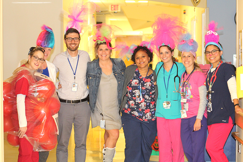 Seven members of the pediatric unit dress as Troll dolls. One dresses as a bag of red blood cells