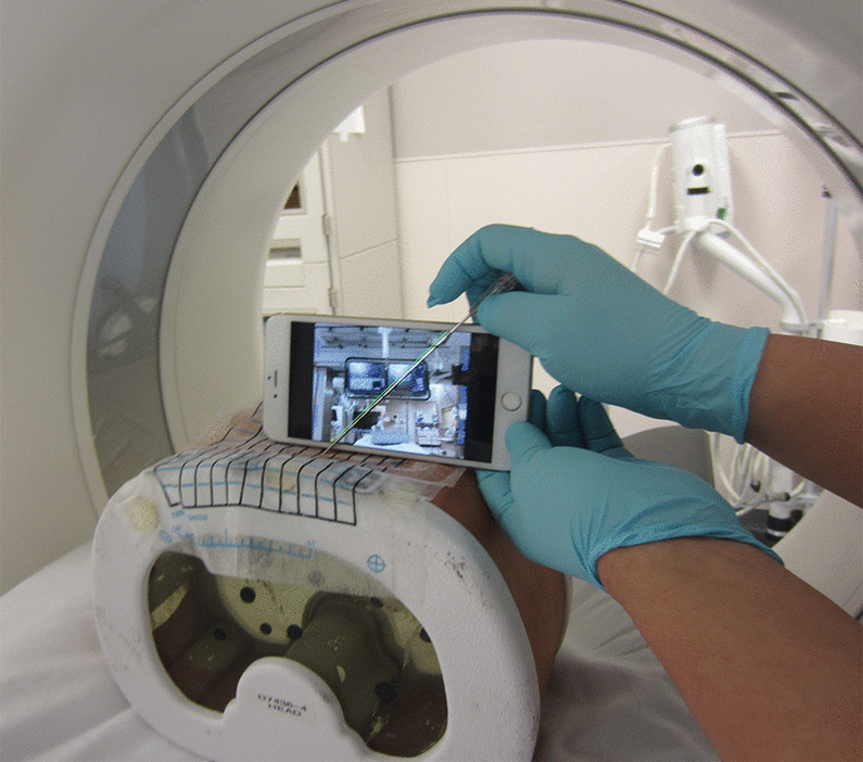 A cell phone held in front of a needle in a CT scanner