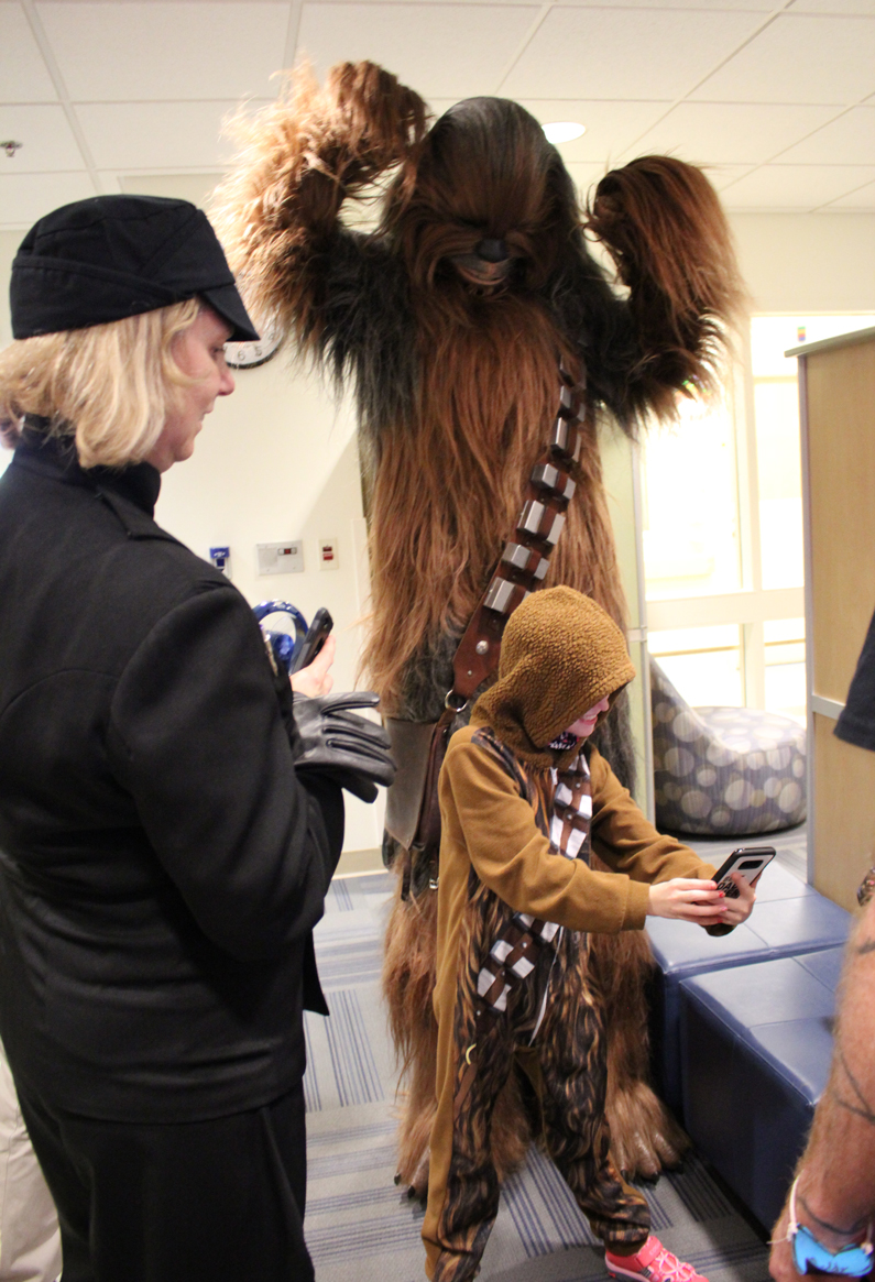 Star Wars Wookiee stands tall above a pediatric patient as she takes a photo of the both of them