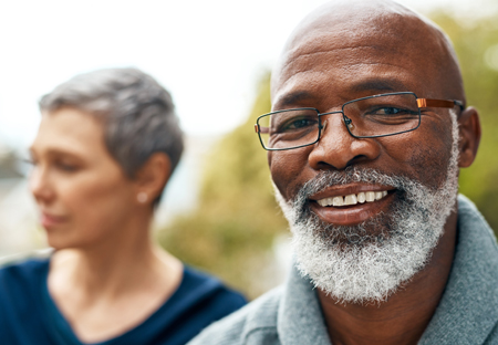 Older African American Man smiling at the camera with women in the background looking away