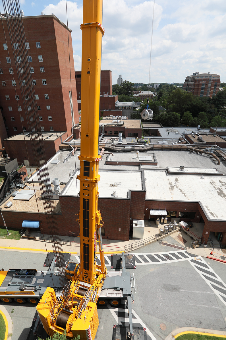 A view from the top of a parking garage to show the crane moving the magnet above the roof of the hospital