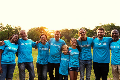 Picture of men, women and children wearing a blue shirt that says volunteer on it