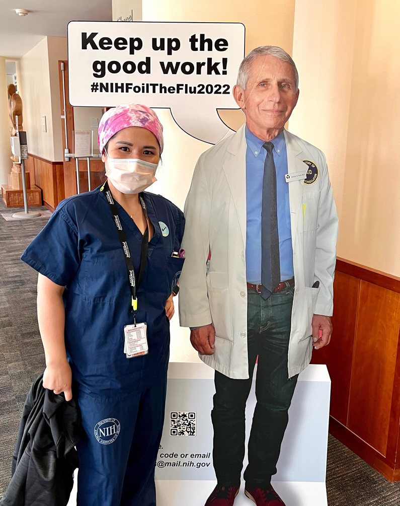 Person in scrubs photographed with cutout of Dr. Anthony Fauci