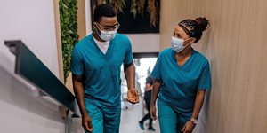 Two hospital staff members converse as walk