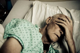 a man in a hospital bed holding his head